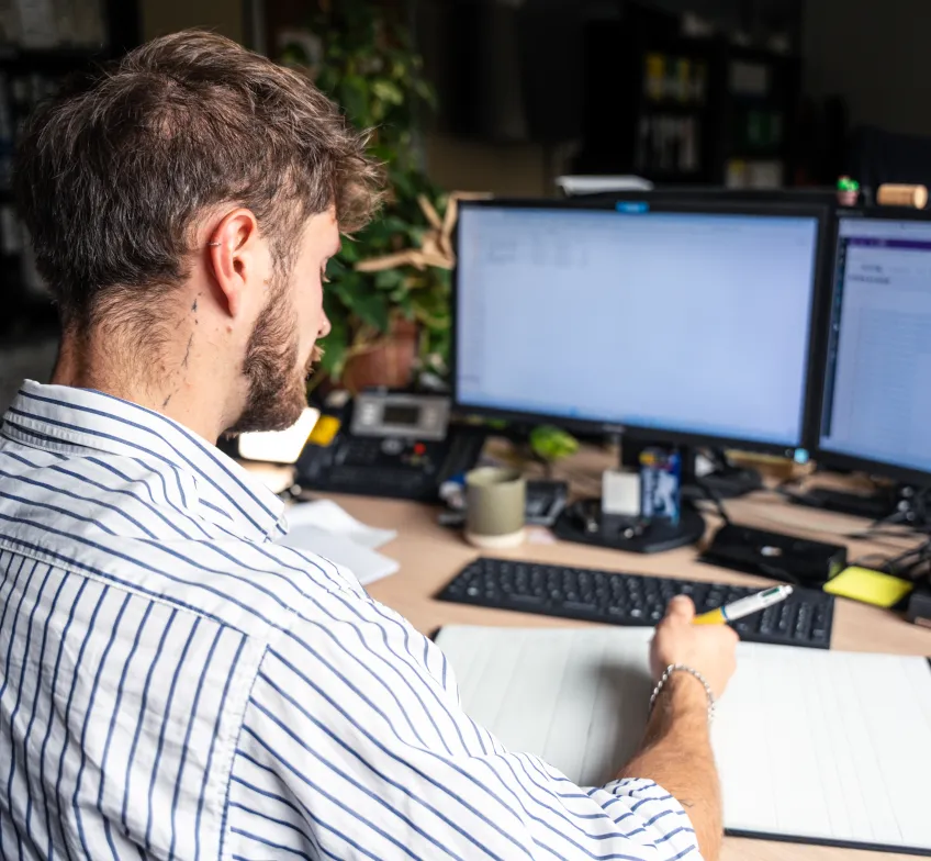 Homme de dos devant écrans d'ordinateur
