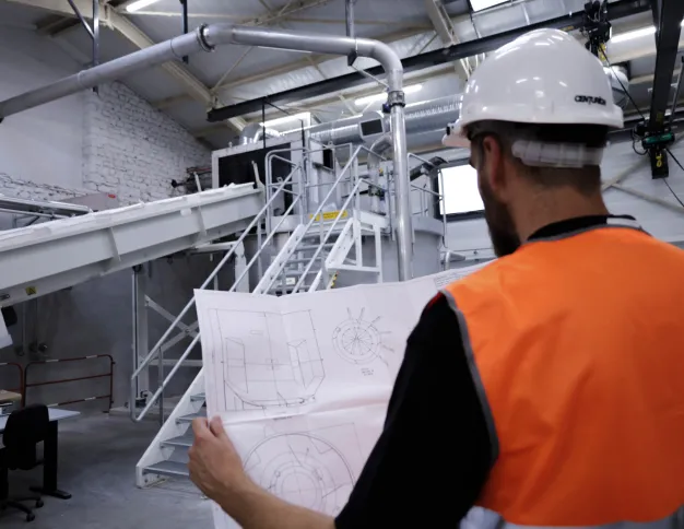 Homme devant une machine avec un plan