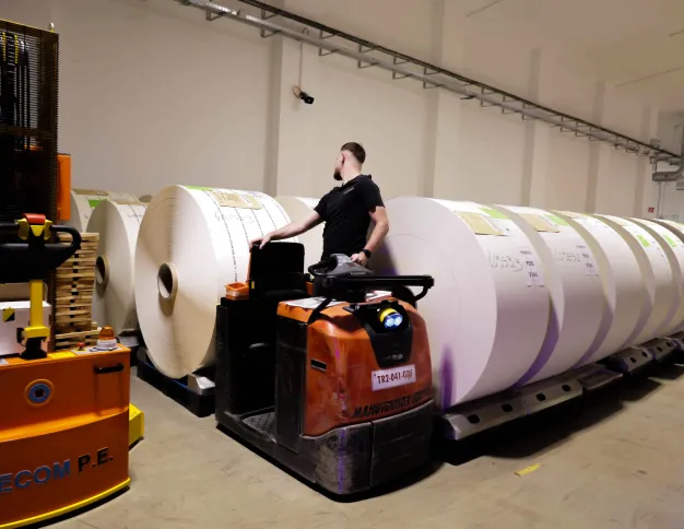 Homme qui transporte des bobines de papier